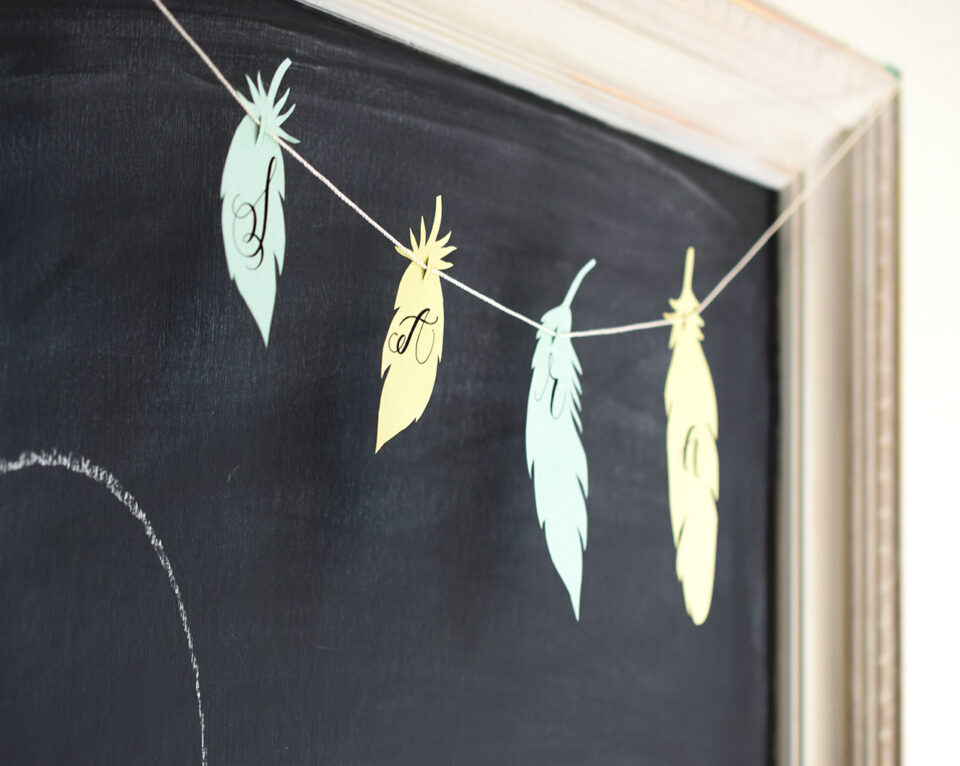 A paper feather garland hung on a chalkboard